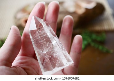 Beautiful Clear Quartz tower, and fresh pink rose flowers. Bright Quartz crystal, healing crystal being held in hand. Woman holding quartz tower, crisp colors in natural lighting. Vibrant meditation.