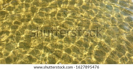 Beautiful clear water with light ripples and a bottom-visible sandy lake on a sunny hot summer day. Concept of Pure Freshwater. Place for text
