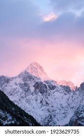Beautiful close up shot of a pink glowing Mountain top in the Alps at sunset while wind is blowing snow off the Mountain into pink and purple clouds. Power of natural elements in an alpine surrounding - Shutterstock ID 1923629735