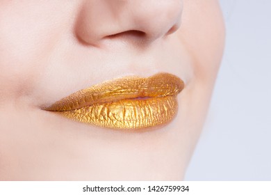 Beautiful closeup female plump lips with gold color makeup