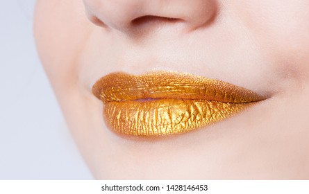 Beautiful closeup female plump lips with gold color makeup