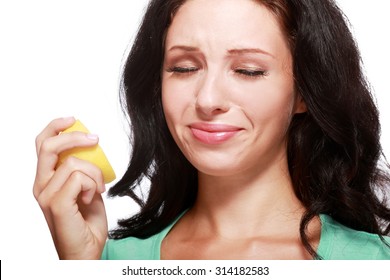 Beautiful close-up portrait of young woman tasting lemon. Sour taste.