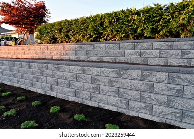 A beautiful closeup view of a grey colored stone block retaining wall build as a two tier wall into an existing garden landscape. - Shutterstock ID 2023259444