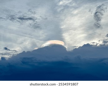 A beautiful cloud formation with subtle rainbow-like colors shining through, creating a calm and atmospheric scene.