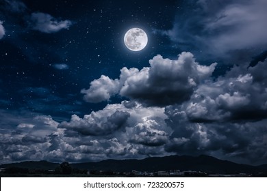 Beautiful cloudscape with many stars. Night sky with bright full moon and dark cloudy above mountain range among town. Serenity nature background. The moon taken with my own camera. - Shutterstock ID 723200575