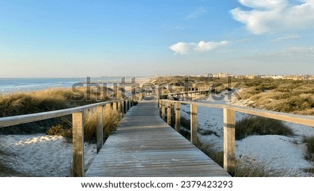 The beautiful coast of Atlantic ocean in Costa de Prata, Portugal. Wooden walkway leading to the beach with blue sky and white clouds.
