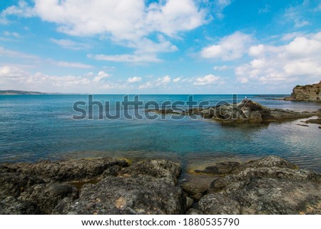 A beautiful coast view of clear blue sea, rocks, cliff and cloudy sky. Seascape of a bay.