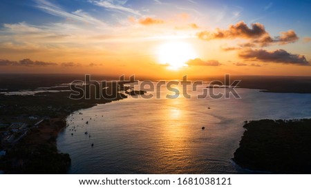 Beautiful coastline in Tibau do Sul during a bright summer sunset with a large river and boats in the background