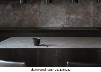 Beautiful coffee cup on island or table countertop in modern home kitchen. Dark grey kitchen design - detail of interior.