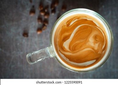 Beautiful coffee milk foam. Coffee with milk in a transparent glass on a dark background top view. - Shutterstock ID 1225590091