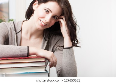 A Beautiful College Girl Leans On A Stack Of Books