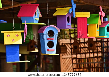 beautiful colored bird houses made of wood hanging in the shop is a household business 
