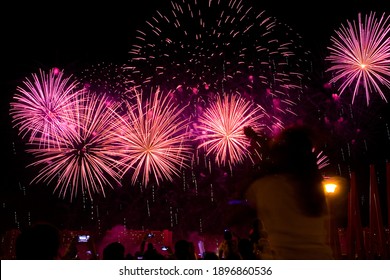 Beautiful colorful fireworks in the evening sky. The audience is watching.