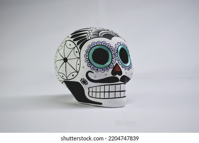 Beautiful and colorful Mexican skull isolated, made of ceramic, and painted by hand. Craft made in Mexico. Turquoise background. Traditional mexican skull for the Day of the Deads.