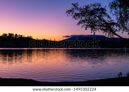 Beautiful, colorful rainbow sunset over a lake with forest and mountains silhouettes in the background. Shot in Lake Placid, NY, USA. 