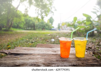 Beautiful colorful selection of beverage in plastic cups on wooden in nature background