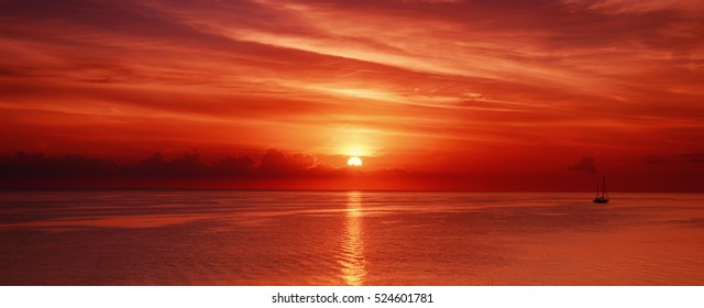 Beautiful colorful sunrise at the sea with dramatic clouds and sun shining
