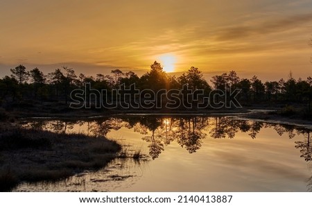 Beautiful, colorful sunset, sunrise over a wide river. Twilight rays and clouds reflected in the calm water.