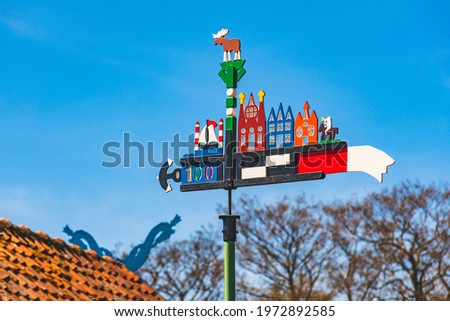 Beautiful colorful weathercock waving in the Curonian Spit in Nida fishermen's village, Lithuania, Europe with blue sky and roof with heads of horses on background 