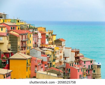 Beautiful colourful historic houses on the hills of Manarola, a popular tourist attraction destination, part of the famous Cinque Terre towns, Italy; UNESCO site. High angle view, sea in background.