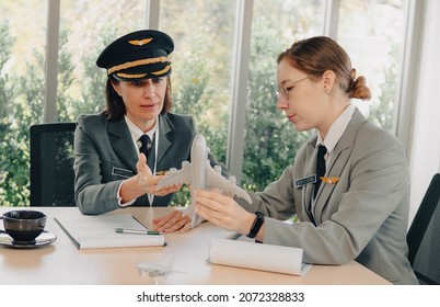 Beautiful Commercial Female Pilot Provides Training To Young Flight Crew. Middle Aged Woman Airplane Captain Instructor Has A Meeting, Discussion About Aircraft With Aircrew. Aviation Business Concept