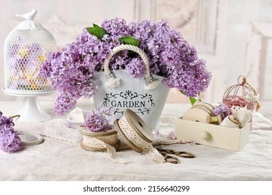 Beautiful composition with bouquet of purple lilac blossoms in metal bucket in shabby chic style interior