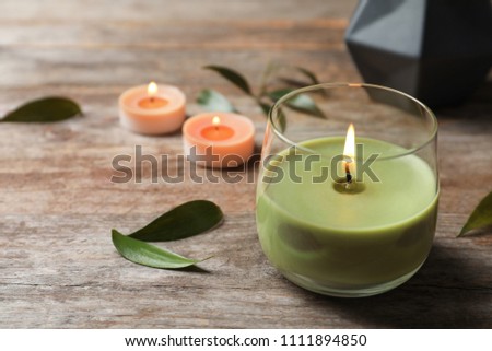 Beautiful composition with burning wax candle on wooden table