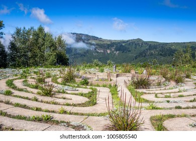 Beautiful concrete path maze at the edge of a mountain overlooking another with clouds drifting