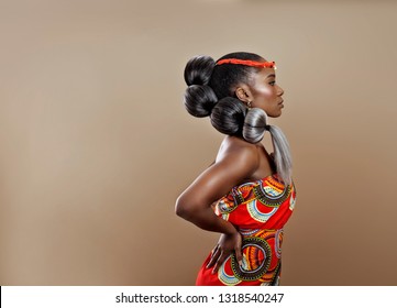 Beautiful confident African woman with intricate hair wearing an African Print dress and beads in her hair
with her hands on her waist in profile pose