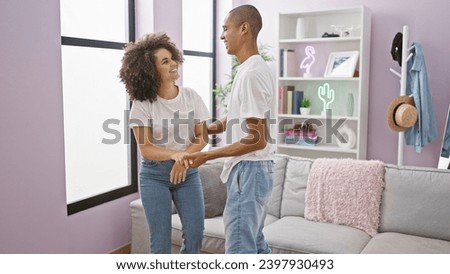 Beautiful, confident couple joyfully dancing and smiling at home, fusing love and happiness through music in their indoor living room
