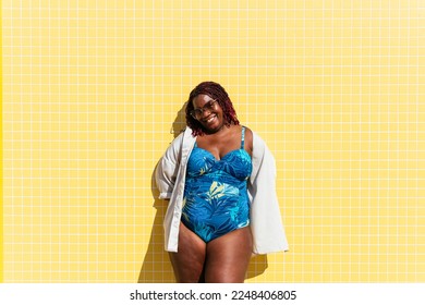 Beautiful and confident plus size woman having fun at the beach, posing on colorful wall background -  concepts about body acceptance, body positive, self confidence and body care - Powered by Shutterstock