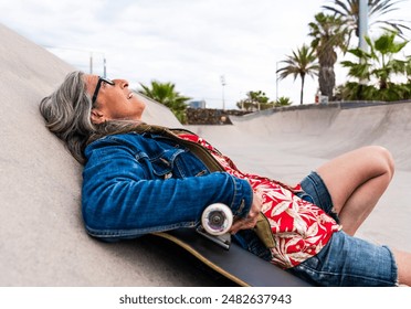 Beautiful confident senior woman with grey hair skateboarding outdoors - Pretty and youthful mature older female adult having fun at city skate park, concepts about elderly and quality of life - Powered by Shutterstock