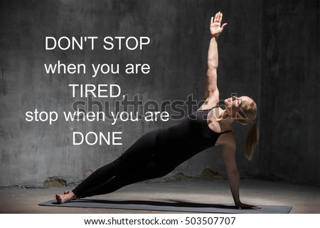 Beautiful cool sporty young woman in sportswear working out indoors against urban dark background, doing Side Plank Pose. Motivational text 