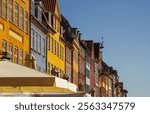 Beautiful Copenhagen, Denmark. Upper part of colorful townhouses in a row with cafes sunshades in the historic picturesque waterfront district of Nyhavn, with copy space.