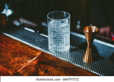 Beautiful Copper Jigger On Wooden Bar Table With Mixing Glass.