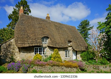 A beautiful country cottage with a thatched roof in spring time, The Cotswolds, Gloucestershire, United Kingdom           