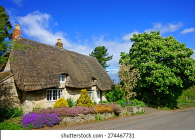 A Beautiful Country Cottage With A Thatched Roof In Spring Time, The Cotswolds, Gloucestershire, United Kingdom