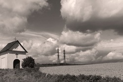 Beautiful Countryside Landscape, Small Chapel At The Field, In The Background Of High Voltage And Sky With Clouds, Outside