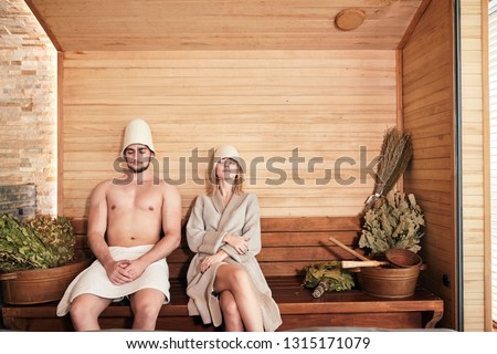 Beautiful couple in bathwear, relaxing in sauna and caring about health and skin, getting free their body and mind of the everyday strains and treat