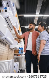 Una hermosa pareja elige un aire acondicionado en casa en una tienda de electrónica.