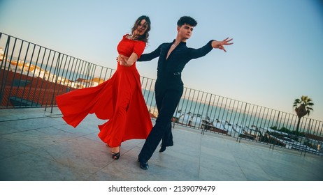 Beautiful Couple Dancing A Latin Dance Outside The City With Old Town In The Background. Sensual Dance By Two Professional Dancers On A Sunset In Ancient Culturally Rich Tourist Location.