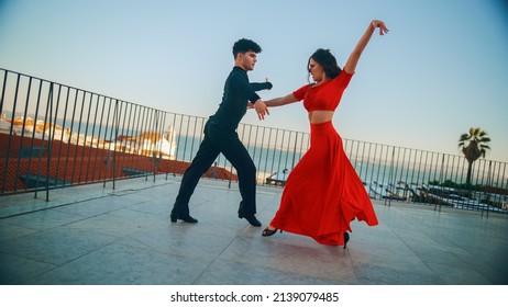 Beautiful Couple Dancing A Latin Dance Outside The City With Old Town In The Background. Sensual Dance By Two Professional Dancers On A Sunset In Ancient Culturally Rich Tourist Location.