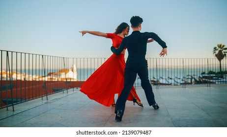 Beautiful Couple Dancing A Latin Dance Outside The City With Old Town In The Background. Sensual Dance By Two Professional Dancers On A Sunset In Ancient Culturally Rich Tourist Location.