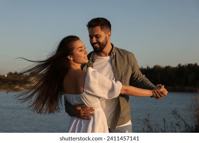 Beautiful couple dancing near river at sunset - Powered by Shutterstock