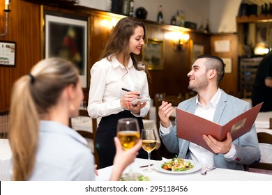 Beautiful couple dining in a restaurant while happy waitress is taking their order