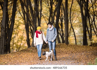Beautiful couple with dog walking in autumn forest - Shutterstock ID 489166735