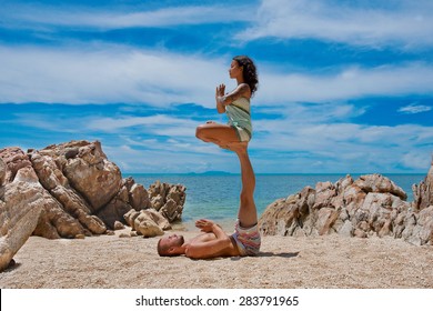 beautiful couple doing acro yoga on the beach - Powered by Shutterstock