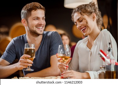 Beautiful couple drinking beverages and having fun in restaurant. Gorgeous young woman and handsome man sitting, laughing and holding glasses of white wine and beer in hands.   - Powered by Shutterstock