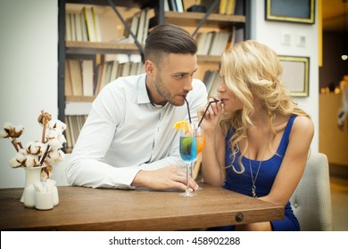 Beautiful Couple Drinking Cocktail From The Same Glass