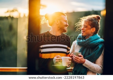 Beautiful couple drinking coffee or tea on the modern terrace in mountains. Copy space. Happy couple drinking coffee and making plans for the day while enjoying each other. Romantic concept.